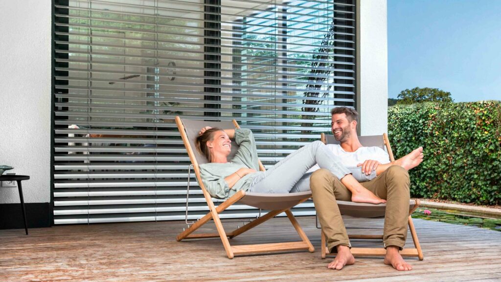 Pärchen auf Liegestühlen vor Raffstore